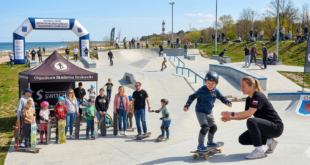 Grupa osób ćwicząca jazdę na deskorolce na skateparku w Świnoujściu pod okiem instruktora.