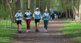 Uczestnicy 445. edycji parkrun Świnoujście biegnący alejkami Parku Zdrojowego w słoneczną, wietrzną pogodę