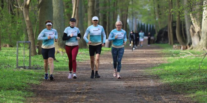 Uczestnicy 445. edycji parkrun Świnoujście biegnący alejkami Parku Zdrojowego w słoneczną, wietrzną pogodę