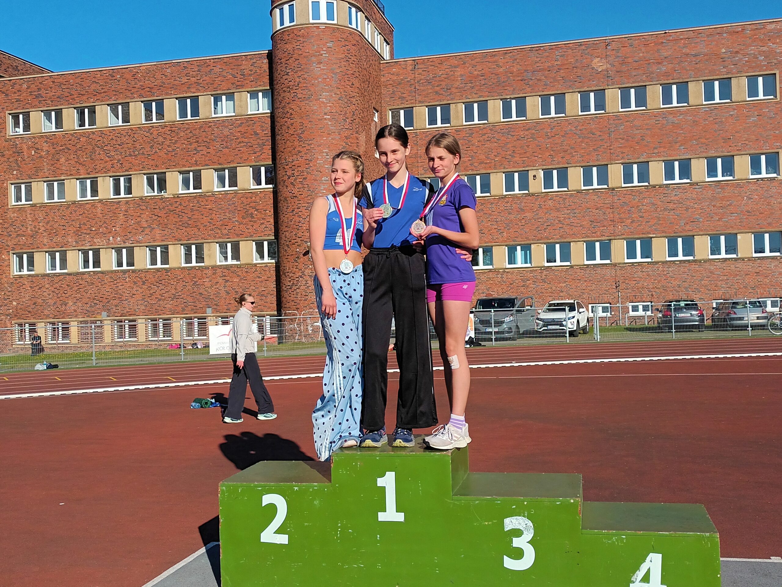 Natalia Smolińska i Helena Grudzień, lekkoatletki klubu OSiR Wyspiarz, uśmiechnięte na stadionie lekkoatletycznym.