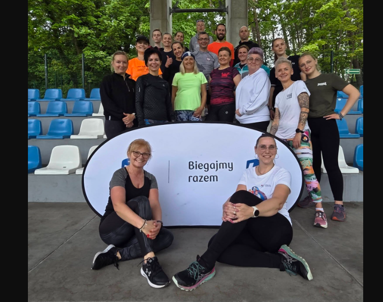 Grupa biegaczy robiąca przysiady na krytych trybunach Stadionu Miejskiego w Świnoujściu podczas deszczowego treningu