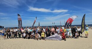 Uczestnicy imprezy Plażowy Nordic Walking w Świnoujściu maszerują z kijami po plaży nad Bałtykiem, na czele z Prezydent Joanną Agatowską.