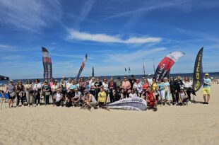 Uczestnicy imprezy Plażowy Nordic Walking w Świnoujściu maszerują z kijami po plaży nad Bałtykiem, na czele z Prezydent Joanną Agatowską.