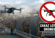Nowoczesny dron unoszący się w powietrzu na tle zablokowanej czerwonym znakiem zakazu panoramy portu w Świnoujściu.