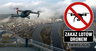 Nowoczesny dron unoszący się w powietrzu na tle zablokowanej czerwonym znakiem zakazu panoramy portu w Świnoujściu.