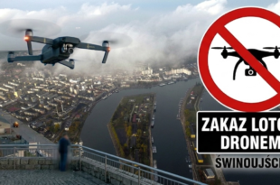Nowoczesny dron unoszący się w powietrzu na tle zablokowanej czerwonym znakiem zakazu panoramy portu w Świnoujściu.