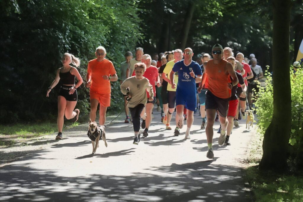 Uczestnicy 452. parkrun Świnoujście biegnący w słoneczny poranek w Parku Zdrojowym.
